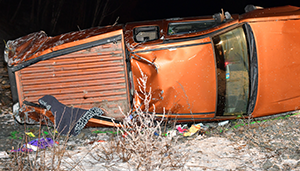 Crashed orange 2004 Chevrolet Pickup truck on its side after the motor vehicle crash